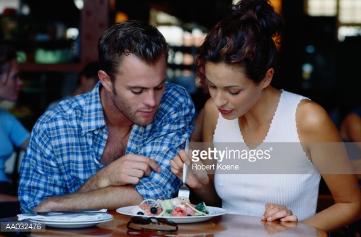 aa032476-couple-sharing-a-plate-of-food-in-a-gettyimages